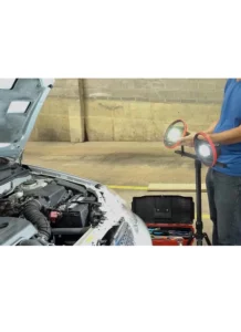 Man using a work light to illuminate the engine of a car