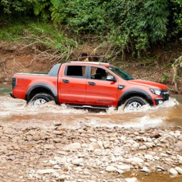 Orange truck driving through a stream