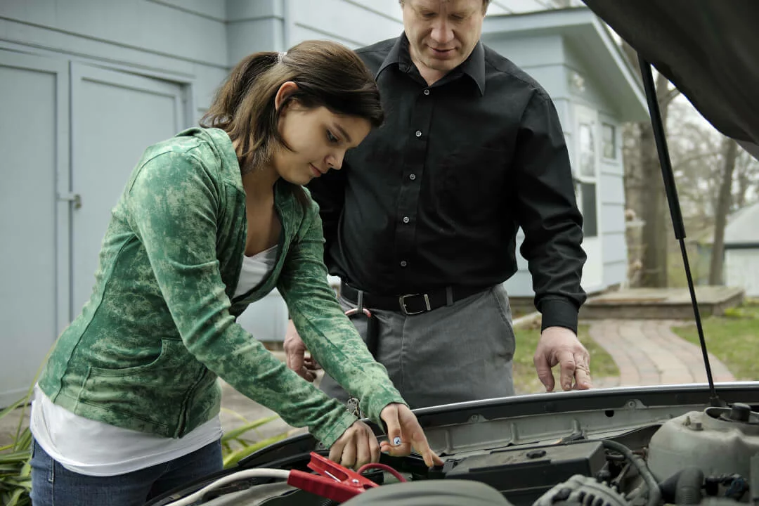 Father and daughter jump starting a car